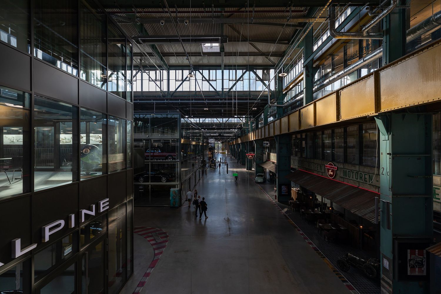 Blick von der Galerie in die lange Halle der Motorworld München mit Stahlträgern und Glasdach
